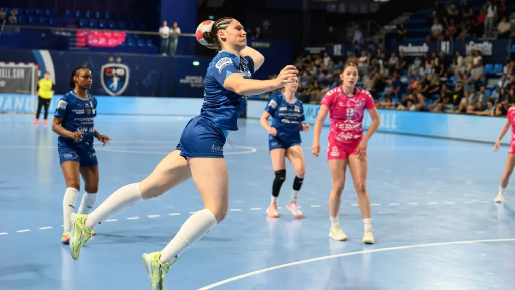 Une joueuse de handball en plein saut s'apprête à tirer au but en plein match.