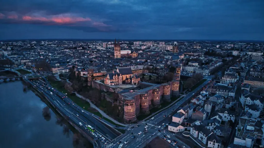 Vue aérienne nocturne illuminée du château d'Angers au coucher du soleil.