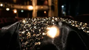 Un tissu noir recouvert de paillettes brillantes dans une salle de spectacle aux lumières floues.