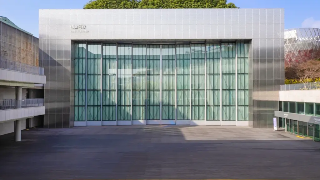 Façade vitrée moderne d'un théâtre urbain ouverte pour un spectacle en plein air.