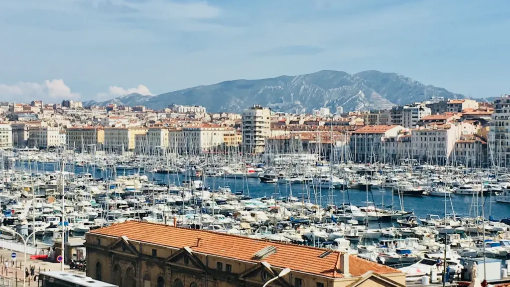 Vue aérienne du Vieux-Port de Marseille avec de nombreux bateaux amarrés au soleil.