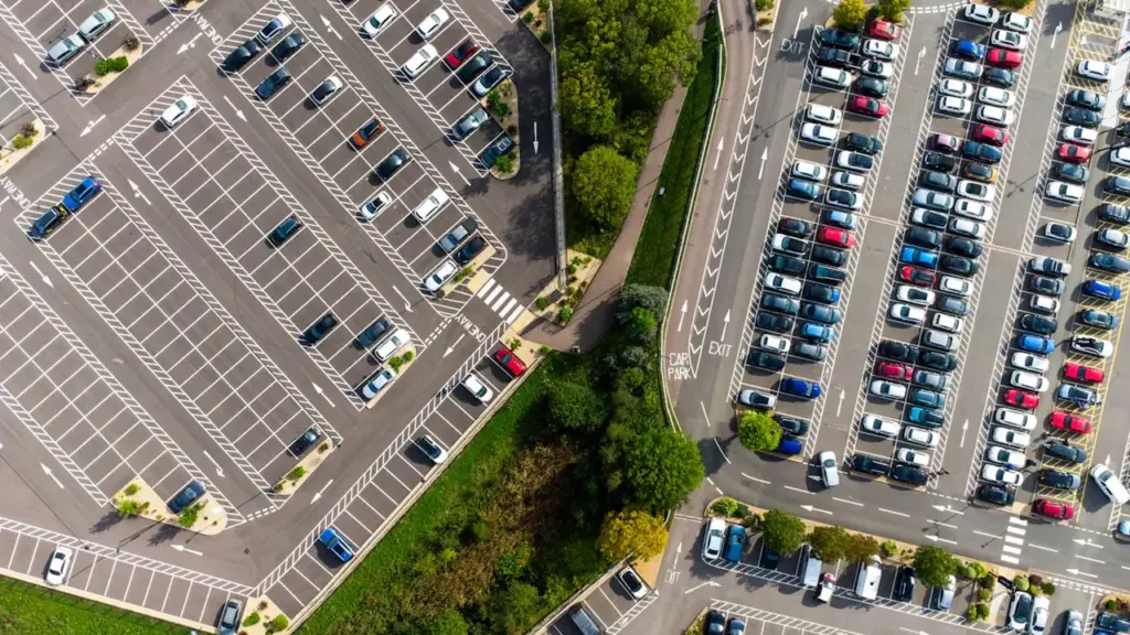 Vue aérienne d'un parking urbain organisé avec de nombreuses voitures stationnées en journée.