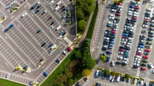 Vue aérienne d'un parking urbain organisé avec de nombreuses voitures stationnées en journée.