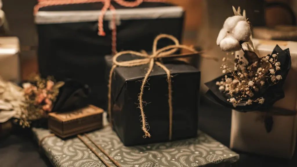 Plusieurs paquets cadeaux élégants et variés sur un tissu à motifs floraux.