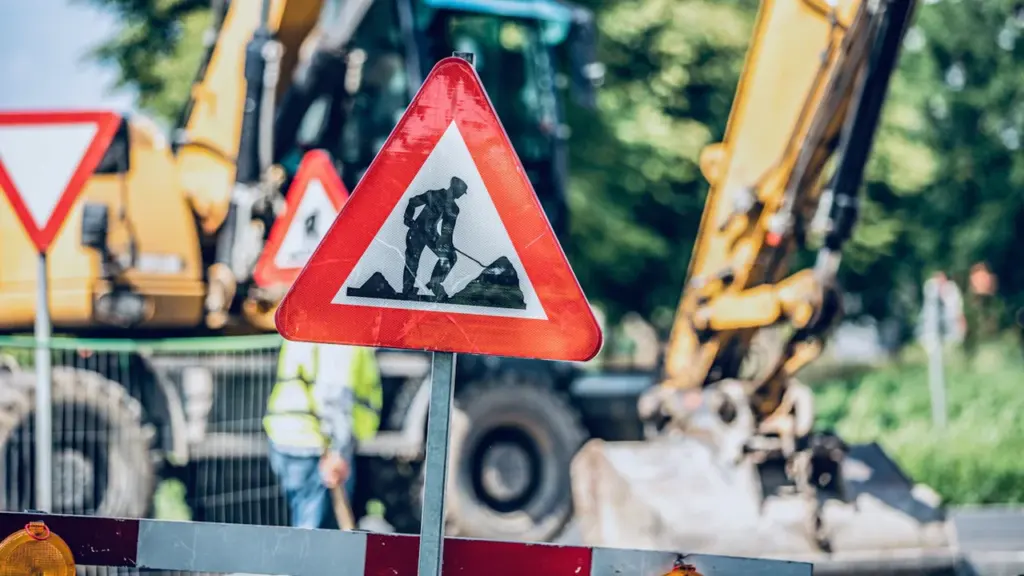 Panneau de signalisation travaux routiers sur fond de chantier urbain en plein jour.