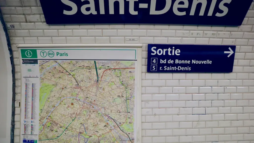 Signalétique de métro indiquant Saint-Denis sur un mur en carrelage blanc classique