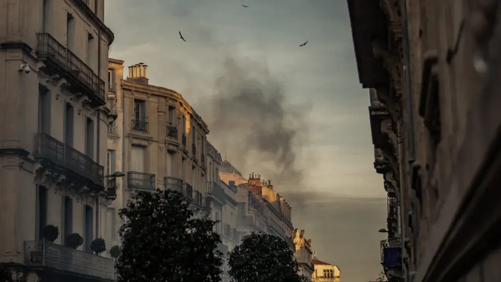 Panache de fumée sombre s'élevant au-dessus d'immeubles résidentiels en zone urbaine.