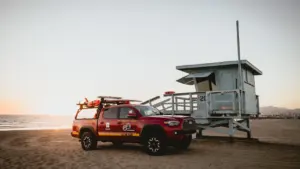 Un pick-up de sauvetage stationné sur une plage devant un poste de surveillance.