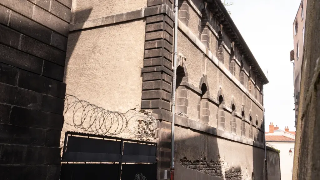 Une rue étroite bordée d'un vieux bâtiment fortifié avec des murs en pierre et barbelés.