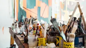 Un atelier artistique avec des pinceaux et pots de peinture sur une table.