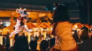 Enfants regardant un spectacle de danse du lion en extérieur le soir.