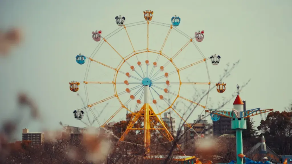 Grande roue colorée dans un parc d'attractions sous un ciel bleu dégagé.