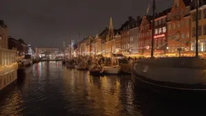 Canal bordé de bateaux et bâtiments illuminés au port, ambiance nocturne à Hyères.