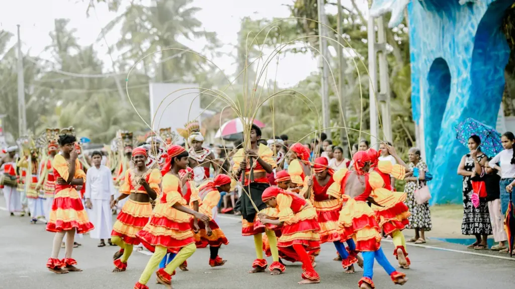 Des artistes en costumes traditionnels jaune et rouge défilent lors d'une fête de rue.