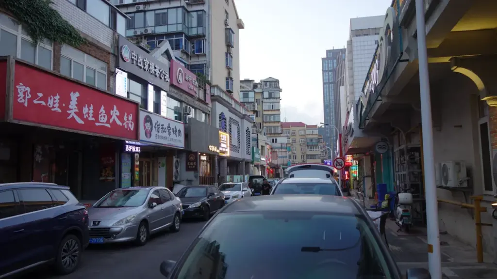 Voitures garées dans une rue urbaine dense avec des façades de bâtiments.