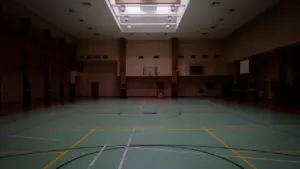 Vue intérieure d'un gymnase moderne rénové avec sol sportif et éclairage zénithal.